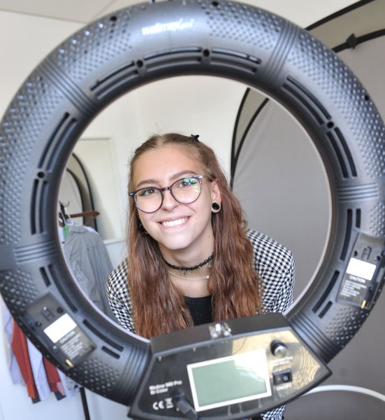 Ein junges Mädchen mit Brille und langen, brünetten Haaren lächelt durch einen Reifen